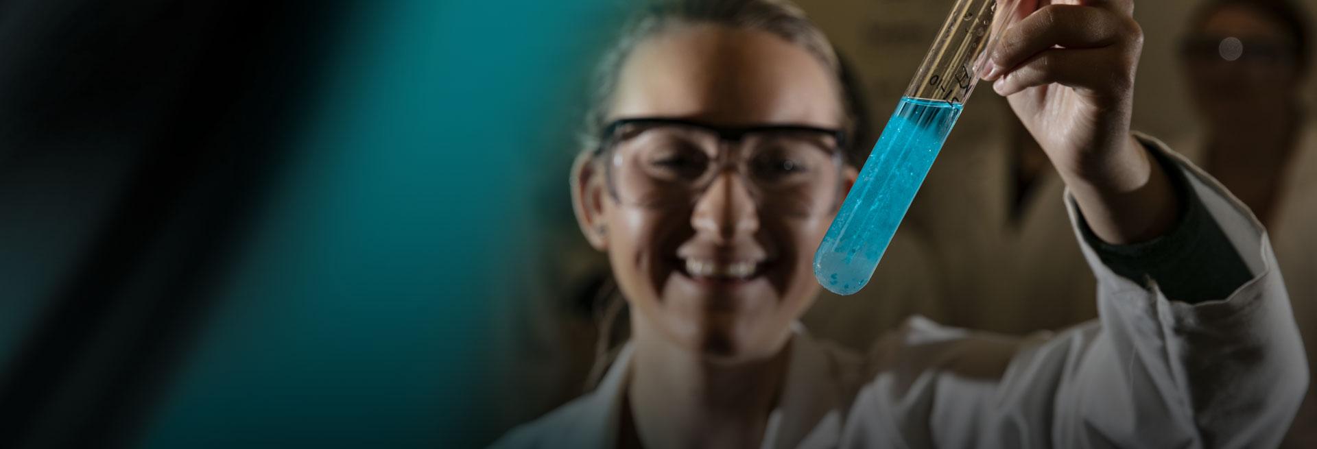 Student holding a test tube on a black and green abstract background